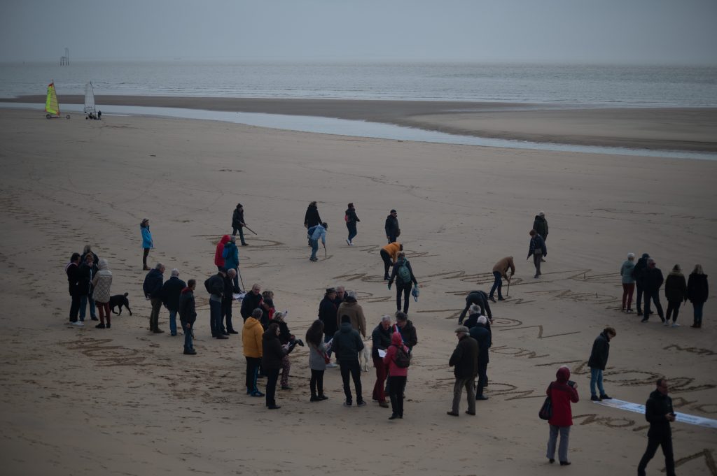 Élus et citoyens gravant Non dans le sable