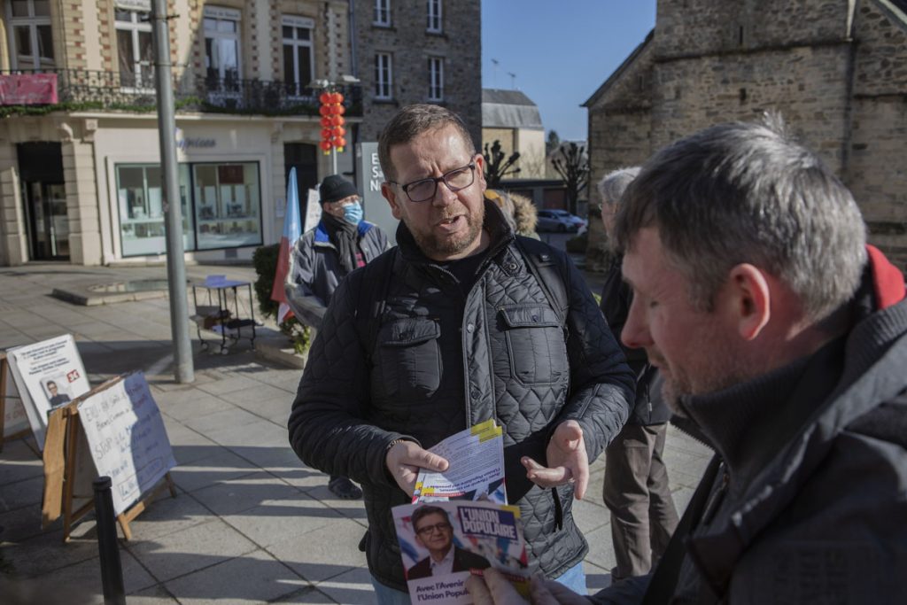 Un membre du comité de soutien de Jean-Luc Mélenchon distribuant des tracts échange avec un passant