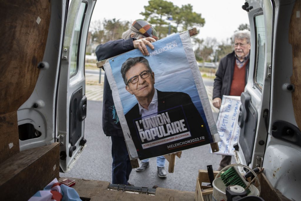 Un membre du comité de soutien de Jean-Luc Mélenchon sort de sa voiture une affiche avec le portrait du candidat.