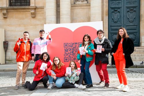 Amélie et des activistes d'associations partenaires de Tous Elus posent pour une photo de groupe devant un grand coeur sur la Place de la Sorbonne