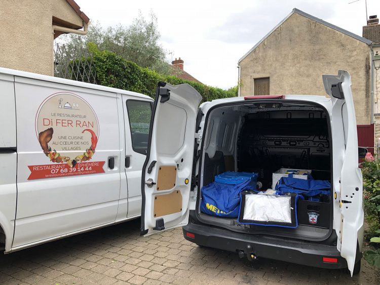 La camionnette décorée du grand logo du restaurateur Di Fer Ran et la fourgonnette du chef sont garées dans la cour de sa maison devant son labo 