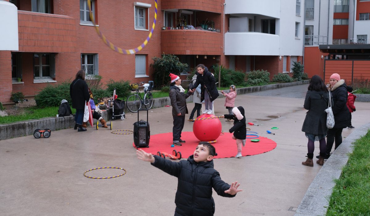 La compagnie Circo Criollo a organisé ce lundi 19 décembre après-midi une séance de cirque pour tous à destination des enfants de la cité Rabelais au Pré-Saint-Gervais (93). Plusieurs familles avec enfants se sont réunies au centre de la cité pour participer à des ateliers de jonglage et de l’art du cirque encadré par les membres de la compagnie.