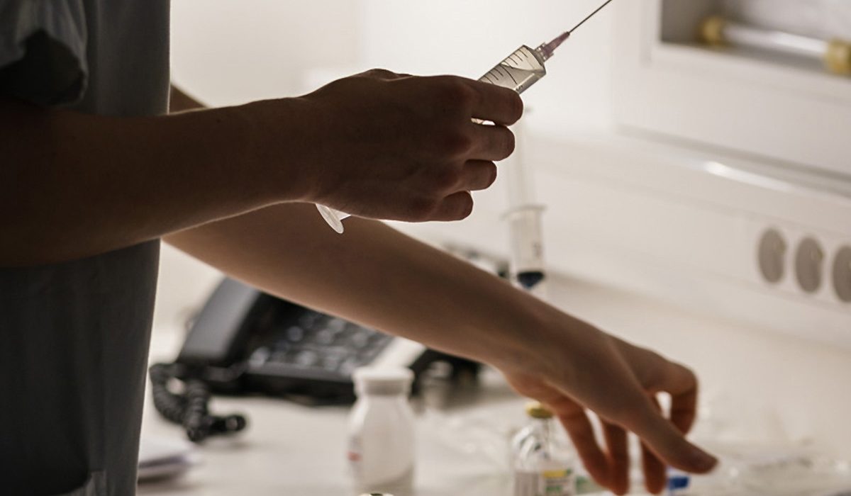Dans le poste de soins, une infirmière prépare son aiguille pour introduire un produit dans la poche à transfuser à un patient greffé © Aurélien Pallier-Colinot