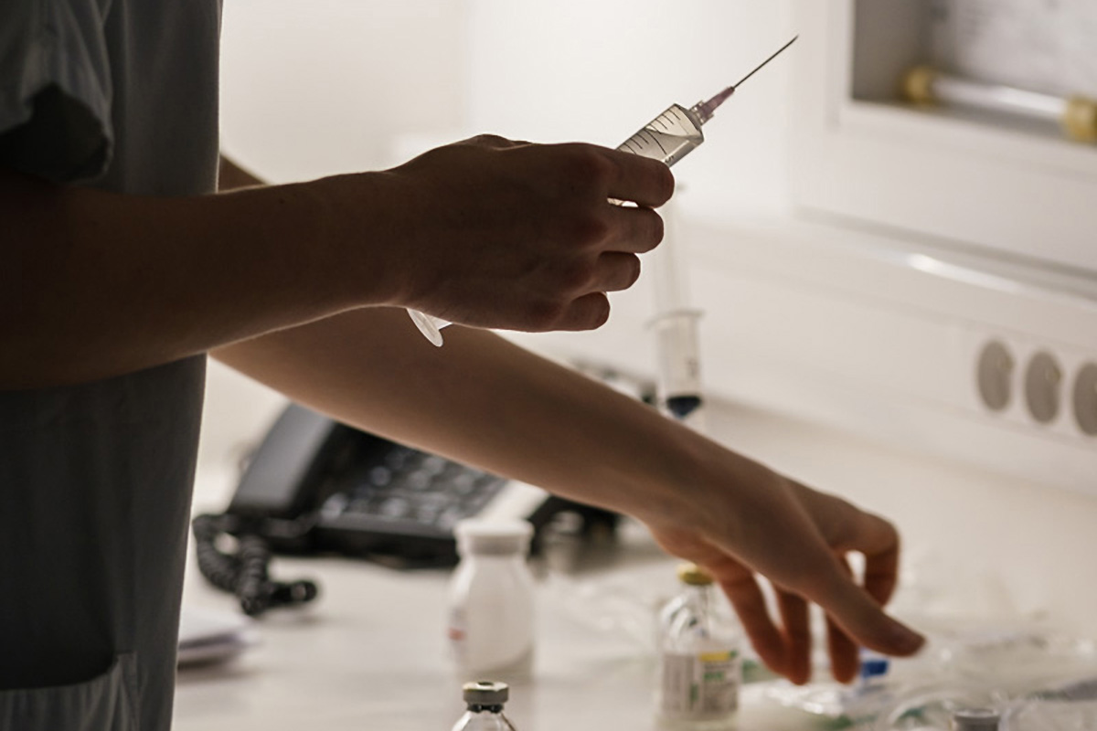 Dans le poste de soins, une infirmière prépare son aiguille pour introduire un produit dans la poche à transfuser à un patient greffé © Aurélien Pallier-Colinot