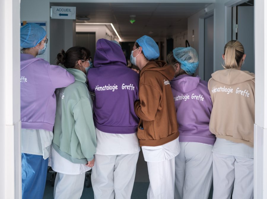 Infirmières et aide-soignante vêtues de leur tenue blanche et de leurs sweats d'équipe estampillés Hématologie greffe Saint-Louis