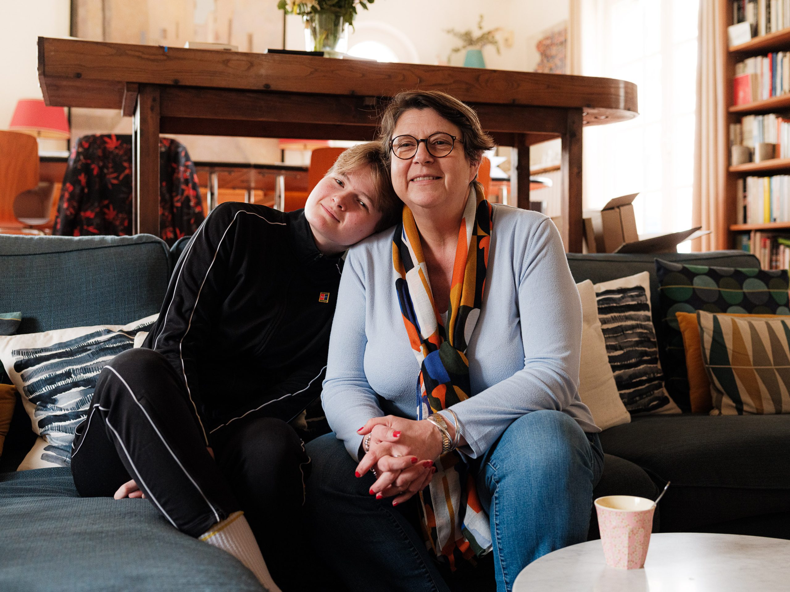 Clem et sa maman partagent des souvenirs sur le canapé du salon, un échange émouvant et intime. Itteville, février 2024.